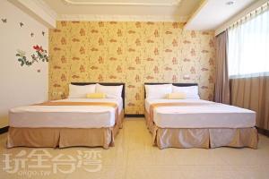 two beds in a room with yellow wallpaper at 伯爵四季休閒民宿 in Jinhu
