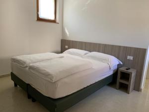 un letto con lenzuola e cuscini bianchi in una camera da letto di Agriturismo Ca' Verde a SantʼAmbrogio di Valpolicella