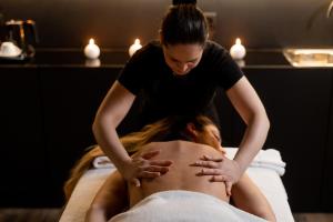 una mujer recibiendo un masaje de espalda de un terapeuta en HF Ipanema Park, en Oporto
