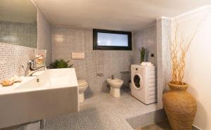 a bathroom with a sink and a toilet and a washing machine at ClickSardegna Villa Paraiba fronte mare per 12 persone in Alghero