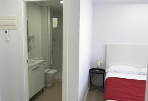 a white bedroom with a bed and a bathroom at Bet Apartments - Reig in Valencia
