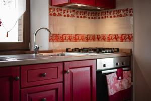 eine Küche mit roten Schränken, einer Spüle und einem Herd in der Unterkunft Appartamento Rosso - Monte Crespini in Manciano