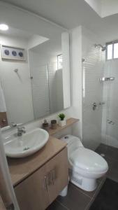 a bathroom with a toilet and a sink and a mirror at Hermoso Apartamento Ricaurte Peñazul La Morada. in Ricaurte