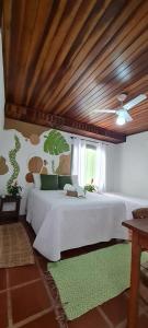 a bedroom with a white bed with a wooden ceiling at Pousada Manga Rosa in Paraty