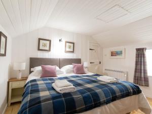 a bedroom with a blue and white bed with pink pillows at Beaton's Croft House - Uig Skye in Portree