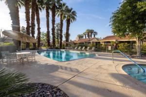a swimming pool with a table and an umbrella at Palm Desert Charm Permit in Palm Desert