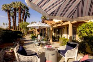 a patio with chairs and tables and palm trees at Palm Desert Charm Permit in Palm Desert