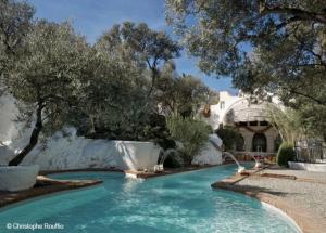 a pool in front of a house with trees at Résidence Cala Montgo in L'Escala