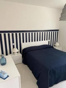 a bedroom with a blue bed with a striped headboard at Bilocale moderno 4 posti vicino al mare in Scarlino