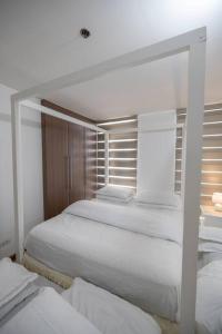 a white bedroom with two beds and a window at A2J Luxury 1BR Balcony Venice Suite Near Malls in Manila