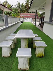 a table and benches sitting on the grass at XHQ Home Stay - PD Mahkota （30 Pax） in Kampong Arab
