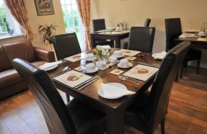 comedor con mesa con sillas negras y mesa en New Farm Cheshire B&B en Winsford