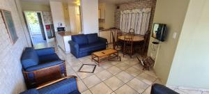 a living room with blue chairs and a kitchen at Pearly Shells in Scottburgh