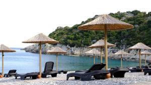 un grupo de sillas y sombrillas en una playa en LİKYA202 APARt OTEL, en Demre