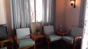 トロにあるPension Alkistisの椅子2脚、テレビ、窓が備わる客室です。