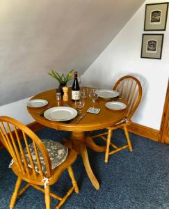 un tavolo in legno con 2 sedie e una bottiglia di vino di Little Glebe a Sherborne