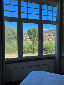 a bedroom with three windows and a bed with a view at Haizea in Bakio