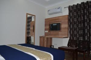 a bedroom with a bed and a flat screen tv at HIMALAYA INN in Pālampur