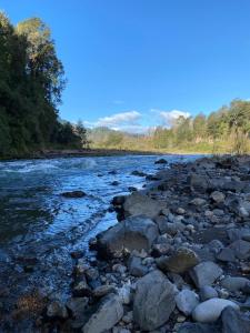 Un río con rocas a su lado en Cabañas Piukewen, en Riñinahue