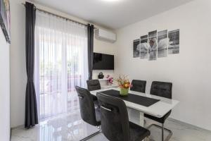 a dining room with a table and chairs and a window at Apartman Naomi in Krk