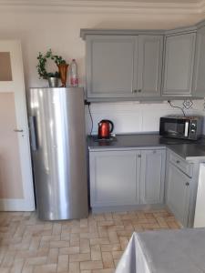 a kitchen with a stainless steel refrigerator and white cabinets at Coquet appartement 6 personnes avec jardin in Wintzenheim +9 photos