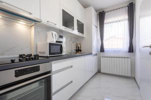 a kitchen with white cabinets and a microwave at Apartman Naomi in Krk