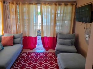 een woonkamer met gordijnen, een bank en een tapijt bij Cays Inn Apartments in Ribishi