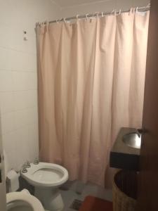 y baño con aseo y cortina de ducha. en Estancia Nueva Córdoba en Córdoba