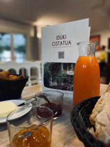 a table with a bottle of orange juice and bread at Les Collines Iduki in Labastide-Clairence