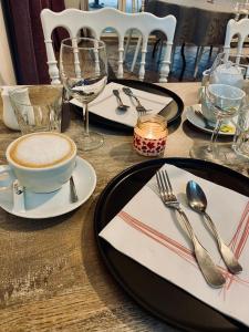 a table with plates and silverware and a cup of coffee at Les Collines Iduki in Labastide-Clairence