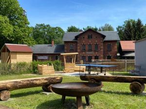 einen Park mit Holzscheiten und einem Tisch und einem Gebäude in der Unterkunft Ferienhaus Bimmelbahn in Olbersdorf