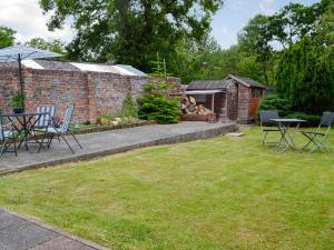 a yard with chairs and a table and an umbrella at Ewenny Cottage in Ewenny