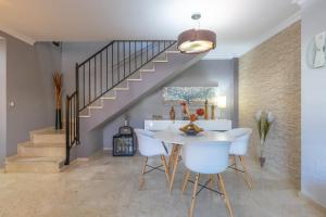 comedor con escalera y sillas blancas en Casa Buda, en Torrequebrada