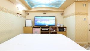 a bedroom with a bed and a flat screen tv at HOTEL MINT HOUSE -resort and relaxation- in Mihama