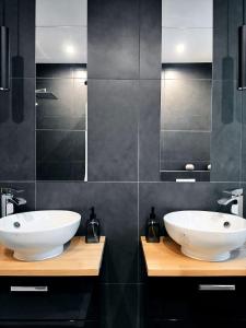 a bathroom with two white sinks and black tiles at Gallery Room 02 in Bielefeld