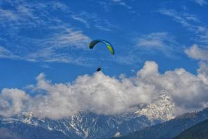 a person flying a kite in the sky over a mountain at Raahi Stay, Landing site Bir - Stay & Cafe in Bīr