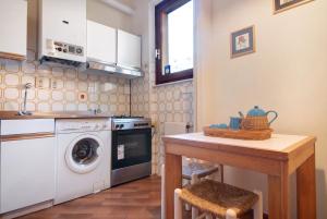 uma cozinha com uma máquina de lavar roupa e uma mesa em Bilocale il Castello con parcheggio em Bonassola