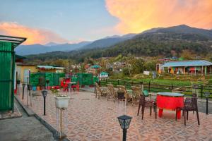 a patio with tables and chairs with a view of a mountain at Raahi Stay, Landing site Bir - Stay & Cafe in Bīr