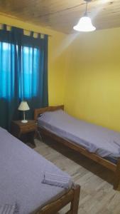 2 camas en una habitación con cortinas azules y lámpara en madre teresa en El Nihuil