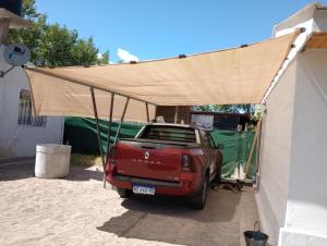 un camión rojo estacionado bajo una cubierta en una casa en madre teresa en El Nihuil