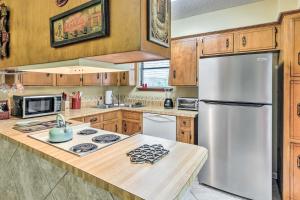 a kitchen with a stainless steel refrigerator and wooden cabinets at Gulf Breeze Vacation Rental 5 Mi to Beach! in Gulf Breeze