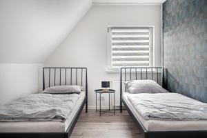 two beds in a room with a window and a table at Noclegi Krańcowa in Zgorzelec +36 photos