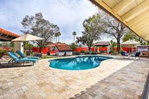 a swimming pool with chairs and an umbrella at Pet-Friendly Glendale Home with Pool and Putting Green in Phoenix