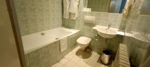 La salle de bains est pourvue d'une baignoire, de toilettes et d'un lavabo. dans l'établissement Grand Hôtel du Havre, à Paris