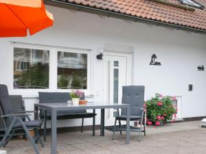 einen Tisch und Stühle auf einer Terrasse mit einem orangenen Regenschirm in der Unterkunft Ferienwohnung Am Eiberg in Bad Wildbad