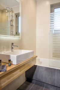 uma casa de banho com um lavatório branco e uma banheira em Vardians Villas & Suites em Caristo