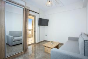 a living room with a couch and a chair and a television at Vardians Villas & Suites in Karistos