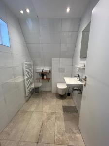 Katwijk aan ZeeにあるAppartement 5の白いバスルーム(洗面台2台、トイレ付)