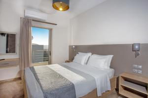 um quarto de hotel com uma cama e uma janela em Vardians Villas & Suites em Caristo
