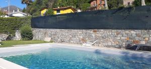 a swimming pool in front of a stone wall at Residence Il Bosso in Domaso